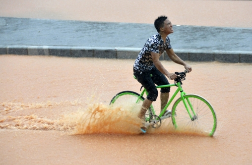 5月11日，一名行人在深圳街頭冒雨騎行。
