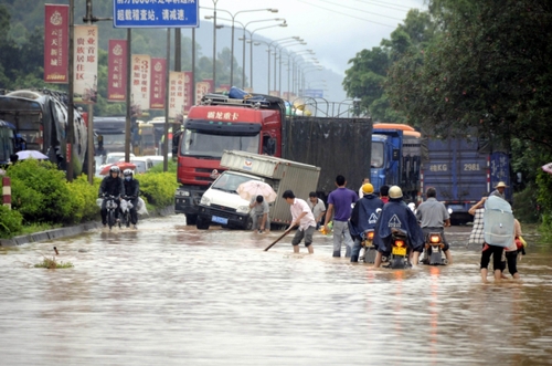 5月18日，國(guó)道324線廣西興業(yè)縣石南鎮(zhèn)黑石嶺路段被洪水淹沒(méi)，一名群眾手持木棍為摩托車(chē)探路。