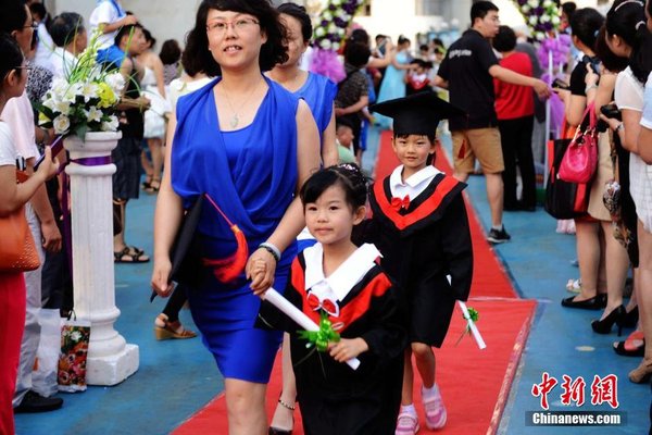 6月28日，山東青島開發(fā)區(qū)第一幼兒園怡和嘉園分園2014級大班舉行畢業(yè)典禮，全體畢業(yè)生身著學(xué)士服在盛裝父母的陪同下，依次走過紅毯，在畢業(yè)榜上鄭重簽下自己的名字，其氣勢不輸當(dāng)紅影星紅毯秀。中新社發(fā) 俞方平 攝 圖片來源：CNSPHOTO