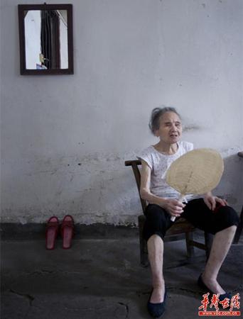 　90歲的王仲蓮如今已患有間歇性的老年癡呆，時(shí)而清醒、時(shí)而糊涂。圖為王仲蓮老人靜坐在屋內(nèi)，搖著蒲扇。