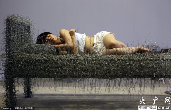 2014年8月11日，北京，中國女藝術(shù)家周潔在北京現(xiàn)在畫廊的展廳睡在一個未完成的鐵絲床上，這一藝術(shù)項目被命名為“36天”，而這36天里，她可以正常進(jìn)食、洗漱、如廁，以及玩手機(jī)等。