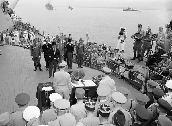 1945年9月2日上午9時(shí)，東京灣，密蘇里號(hào)戰(zhàn)列艦上的日本投降文件簽署儀式。這張照片里，梅津美治郎將軍代表日本武裝力量簽署投降書，（他身后戴著大禮帽的）日本外相重光葵之前已經(jīng)代表日本政府簽字。