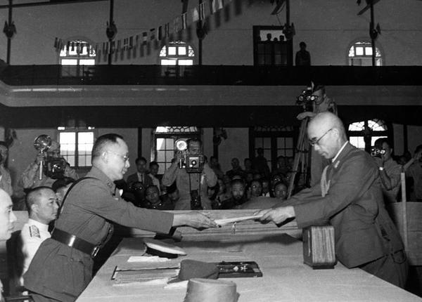 中國戰(zhàn)區(qū)的日本投降儀式上，日本中國派遣軍總司令官岡村寧次在對華投降書上簽字，并向中方交出他的隨身佩刀，以表示侵華日軍正式向中國繳械投降。這是何應欽(左)在南京代表中國政府接受侵華日軍總司令岡村寧次的投降書。