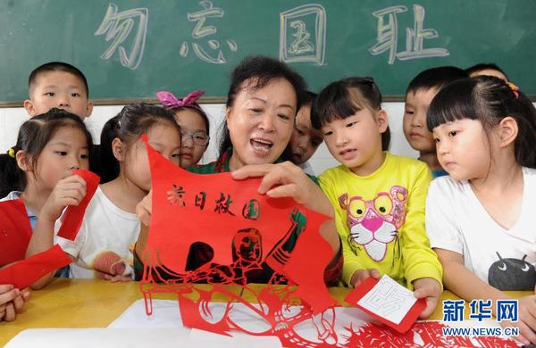 9月17日，剪紙老師宋麗文（中）在教孩子們制作以紀(jì)念“九一八”為主題的剪紙作品。當(dāng)日，安徽合肥市蚌埠路第三小學(xué)開展“勿忘國恥，振興中華”為主題的“九一八”愛國主義教育活動(dòng)，社區(qū)剪紙老師宋麗文現(xiàn)場教孩子創(chuàng)作剪紙作品，教育學(xué)生銘記歷史、熱愛祖國。新華社記者 杜宇 攝