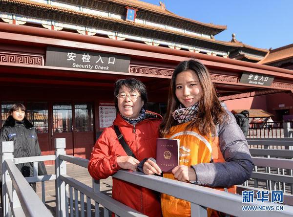 12月3日，一名教師（右）在故宮博物院入口處展示教師資格證。