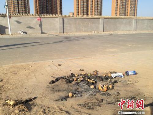 親人在何建華遇害處燃燒的紙錢和祭品。 王天譯 攝