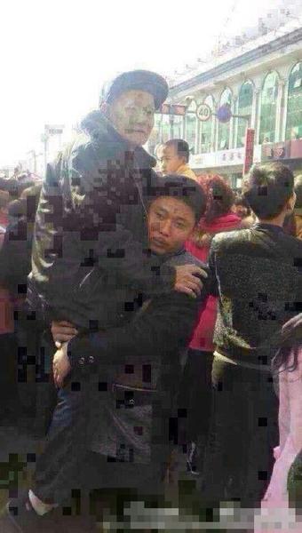 被抱起的老者，年紀(jì)大約70多歲，手持拐杖，穿戴一新。
