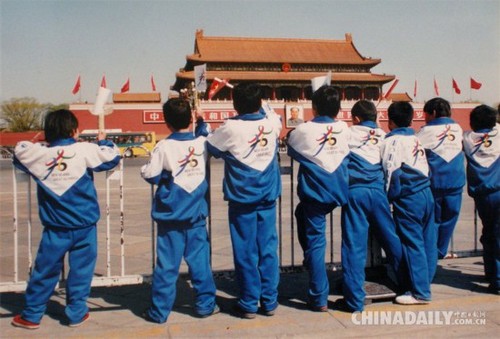 2001年春，北京天安門廣場，幾位身穿印有奧運(yùn)五環(huán)圖案校服的小學(xué)生舉目遠(yuǎn)望，期盼北京奧運(yùn)早日申辦成功。（2001年7月使用膠片拍攝，2008年12月14日數(shù)碼翻拍）