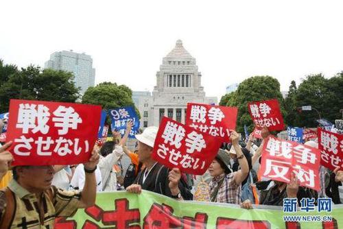 2015年7月14日，日本民眾在國會外集會，手舉標(biāo)語牌，高喊口號示威，抗議新安保法