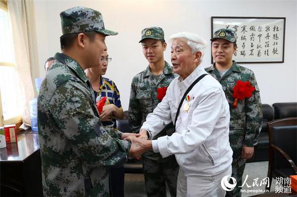抗戰(zhàn)老兵方耀寰握住入伍新兵的手，囑咐他們要收好香港地區(qū)的繁榮與和平，在軍隊(duì)努力學(xué)習(xí)，為國貢獻(xiàn)。 胡丹  攝