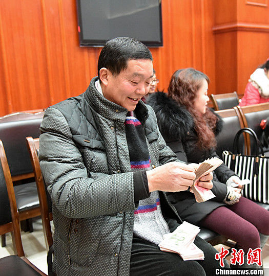 圖為農(nóng)民工清點自己領(lǐng)到的錢。中新社記者
