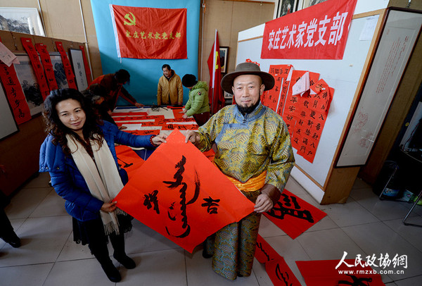 北京宋莊藝術(shù)家黨支部書(shū)記巴特爾把用蒙漢兩種文字寫(xiě)好的春聯(lián)送給蒙族在京的老鄉(xiāng)，祝愿新年吉祥。_副本
