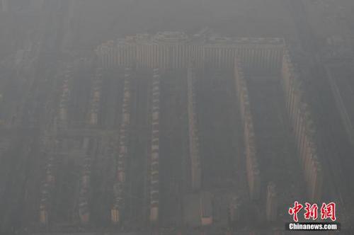 資料圖：2015年12月21日，北京上空航拍空氣重污染，地面建筑若隱若現(xiàn)。12月18日，北京再次發(fā)布紅色預(yù)警，12月19日7時至12月22日24時啟動空氣重污染紅色預(yù)警措施。實施機動車單雙號行駛、建議中小學(xué)幼兒園停課等措施。 <a target='_blank' href='http://www.chinanews.com/'>中新社</a>記者 廖攀 攝