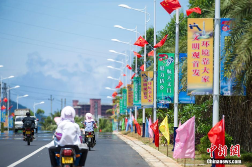 6月24日，海南省文昌市龍樓鎮(zhèn)街道兩側(cè)五星紅旗迎風(fēng)飄揚(yáng)，火箭“首發(fā)”宣傳廣告隨處可見(jiàn)。長(zhǎng)征七號(hào)運(yùn)載火箭發(fā)射日期臨近，中國(guó)首個(gè)濱海航天發(fā)射中心——文昌航天發(fā)射場(chǎng)所在地海南省文昌市龍樓鎮(zhèn)將迎來(lái)“首發(fā)”，中國(guó)的“卡納維拉爾角”正揭開(kāi)神秘面紗。中新社記者 駱云飛 攝