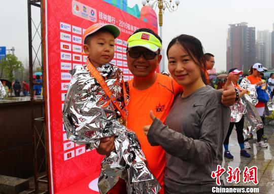 來自廣州的李強(qiáng)夫婦用兒童車，載著4歲的兒子，一家三口完成了在桂林舉行的半程馬拉松比賽?！W惠蘭 攝