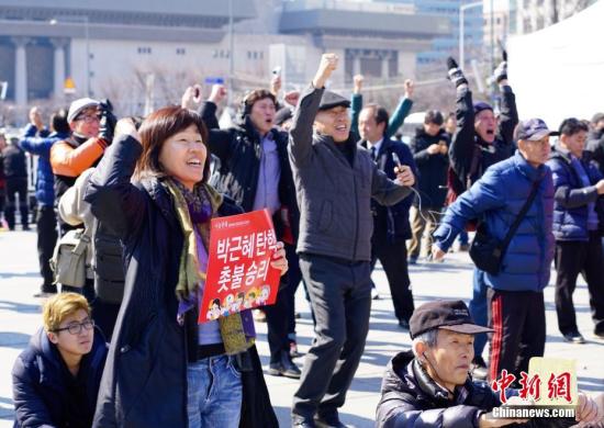 3月10日，在象征著韓國(guó)政治中心的首爾光化門(mén)廣場(chǎng)，民眾在聽(tīng)到憲法法院對(duì)總統(tǒng)樸槿惠彈劾案的審判結(jié)果后歡呼。韓國(guó)憲法法院當(dāng)日作出裁決，宣布彈劾案成立。樸槿惠成為韓國(guó)歷史上首位被彈劾罷免的總統(tǒng)。<a target='_blank' href='http://www.chinanews.com/'>中新社</a>記者 吳旭 攝