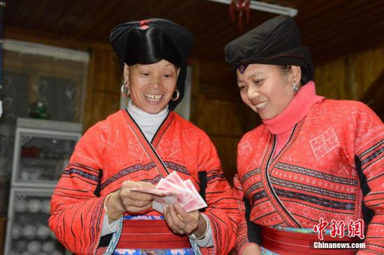 1月27日，廣西龍勝各族自治縣龍脊鎮(zhèn)大寨村的瑤嫂正在清點分到的梯田維護費。1月27日至1月28日，廣西龍勝各族自治縣龍脊鎮(zhèn)大寨村村委會將110多萬元的“紅利”分發(fā)到200多戶的群眾手中。龍脊鎮(zhèn)大寨村從2003年開寨接待游客以來，該縣通過旅游扶貧方式引導該村群眾以梯田入股方式與當?shù)氐凝埣孤糜喂韭?lián)營，旅游公司則將門票收入按一定的比例為當?shù)氐拇迕癜l(fā)放梯田維護費。目前，大寨村的游客多了，大部分村民開設了農家旅館，和販賣瑤族工藝品等，使其成為當?shù)厝罕娫鍪罩赂坏闹饕馈?lt;a target='_blank' href='http://www.chinanews.com/'>中新社</a>發(fā) 韋吉陽 攝