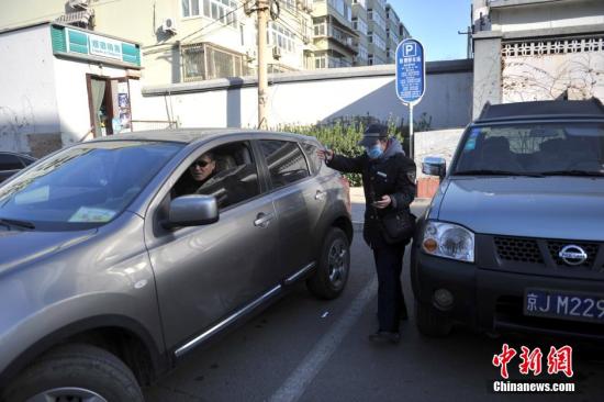 今年元月起，北京全市3000多名路側(cè)停車管理員上崗證更換，新上崗證標(biāo)有二維碼，市民用手機(jī)掃描即可看到管理員的照片、姓名、所在公司、監(jiān)督電話等詳細(xì)信息。若冒用或偽造，掃描出來的信息將與實(shí)際不符，一旦遇到假收費(fèi)員，市民有權(quán)拒絕交費(fèi)。圖為停車場管理員張大姐為車主指揮倒車。<a target='_blank' href='http://www.chinanews.com/' >中新網(wǎng)</a>記者 金碩 攝