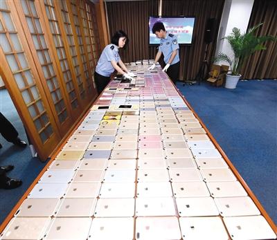 北京警方破獲特大盜銷手機(jī)團(tuán)伙，起獲的525部被盜手機(jī)鋪滿了一張大桌子，其中大多是蘋果手機(jī)。	警方供圖
