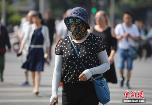 資料圖：5月17日，北京街頭的民眾防曬出行。當(dāng)日北京市氣象臺發(fā)布今年首個高溫黃色預(yù)警。<a target='_blank' href='http://www.chinanews.com/'>中新社</a>記者 楊可佳 攝