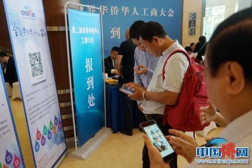 第二屆華僑華人工商大會報到現(xiàn)場，中國新聞社“僑寶”客戶端及中國僑網(wǎng)微信宣傳品吸引了高度關注，嘉賓紛紛掃碼下載。付強 攝