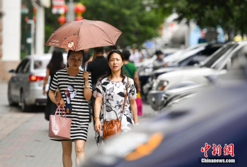 新疆烏魯木齊市街頭，民眾打傘抵擋高溫天氣。