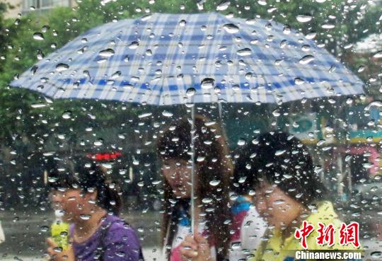 6月28日，隔著滴滿雨珠的車窗，打著雨傘的市民在南京街頭經(jīng)過。泱波　攝