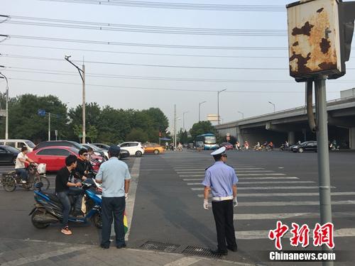 6月21日上午，北京仰山橋下十字路口，執(zhí)勤人員要求非機(jī)動車停在停止線后。湯琪 攝