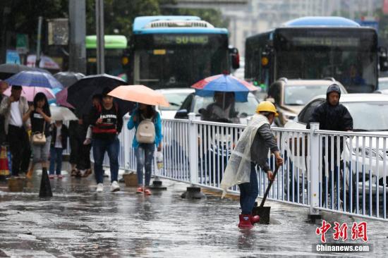 資料圖：行人在雨中出行。 黃芷昕 攝