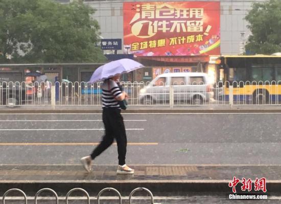 6月23日清晨，北京市民冒雨出行。 中新網(wǎng)記者 富宇 攝