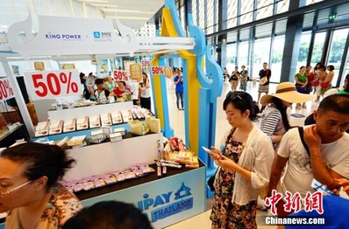 資料圖：某消費(fèi)者在線下商品展臺(tái)前選購(gòu)。