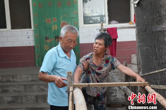 為讓妻子慢慢學(xué)會(huì)走路，李文生每天扶著妻子一遍一遍練習(xí)走路?！±钤杭t 攝