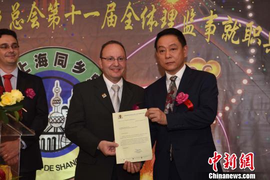 圖為巴西圣保羅市政廳代表給巴西上海同鄉(xiāng)總會會長鄭小云(右一)遞交賀信?！∧尚?攝