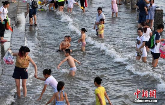 7月4日傍晚，市民們帶著小孩在海邊戲水消暑。連日來，受副熱帶高壓影響廈門地區(qū)持續(xù)高溫。 張斌 攝