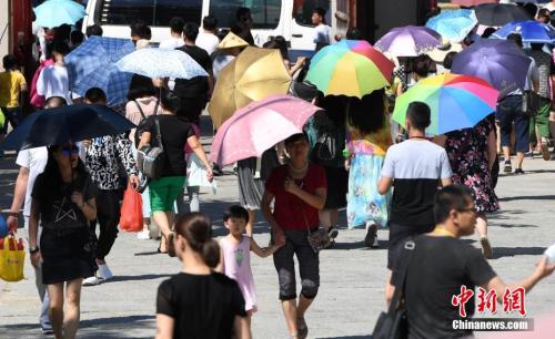7月12日，廈門一景點(diǎn)游客們紛紛打起傘遮擋烈日。張斌 攝