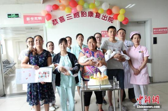 圖為醫(yī)護(hù)人員和三胞胎及家人合影。 鐘欣 攝