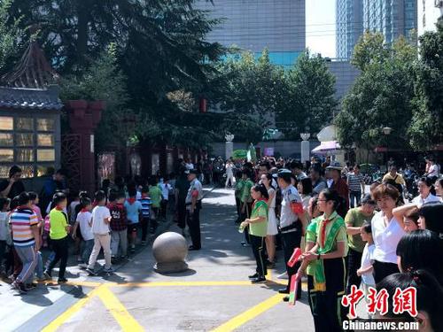 圖為學(xué)校門口擠滿了學(xué)生家長?！∶疯O瀧 攝