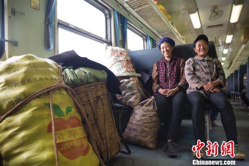 資料圖：穿行大涼山的“扶貧列車”。在普雄開往攀枝花的5633次列車上，兩名到喜德販賣土豆的彝族婦女正守護(hù)著自己的貨品。　龔萱　攝