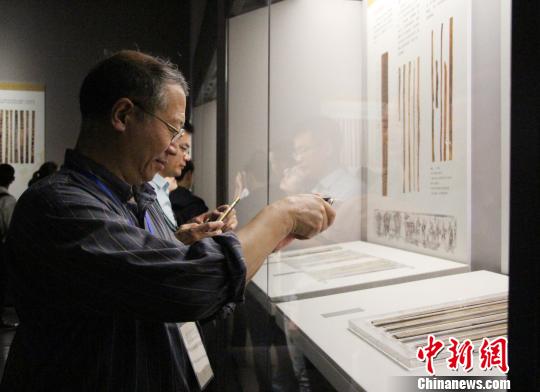 圖為參展觀眾在中國簡帛文化展上觀看和拍攝簡帛文物。　趙曉　攝