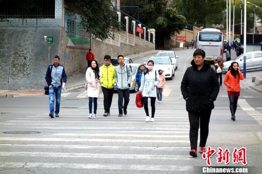 圖為市民們穿著棉服、羽絨服在寒風中卷縮著過馬路。　孫睿 攝