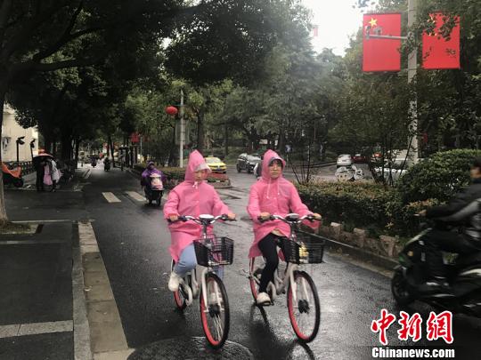 11日，南京迎來降溫降雨。圖為市民披上雨衣出行?！铑伌?攝
