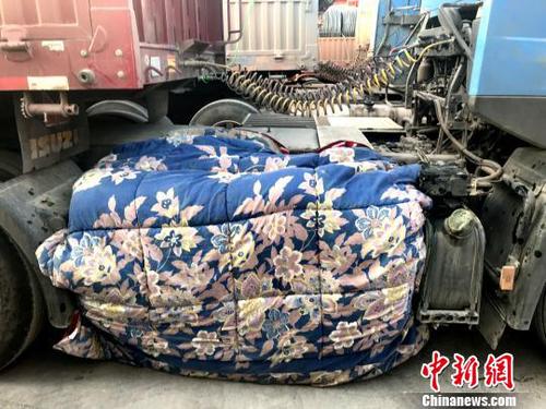 圖為卡車司機(jī)用棉被為卡車“取暖”。　鐘欣 攝