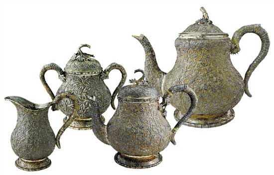 竹林搖曳茶具   Tea Set with Bamboo Forest Pattern　　咖啡壺 通高：18cm；腹徑：13.5cm；重：727g   茶壺 通高：15.5cm；腹徑：10.5cm；重：421g　　糖缸 通高：10.5cm；腹徑：7.5cm；重：186g    奶缸 通高：9.5cm；腹徑：6cm；重：131g　　款識(shí)：儀昌，倫巴 H    這套茶具使用了錘碟工藝，壺身通體附有竹枝竹葉，緊密相間，具有微風(fēng)搖曳之動(dòng)感，壺把手和流均為竹節(jié)附竹葉型。在茶具的細(xì)節(jié)之處體現(xiàn)了匠人的精心設(shè)計(jì)，銀制茶具導(dǎo)熱性極強(qiáng)，為防止茶壺把手過(guò)燙，凡是裝熱飲的茶壺、咖啡壺把手處都裝有一白色象牙制圓環(huán)，俗稱“象牙隔熱”，用以阻斷把手部分的熱傳導(dǎo)，做到美觀大方與實(shí)用功能同時(shí)具備。壺體留有光面盾牌用以刻族徽，壺底外圈鏨刻竹葉紋，有中國(guó)梅蘭竹菊的款式風(fēng)格在里面。該套茶具未經(jīng)任何處理進(jìn)行展示，表面留有一層氧化層，專業(yè)術(shù)語(yǔ)稱之為“包漿”，以為對(duì)比之用。晚清外銷銀器盛極一時(shí)，但缺乏國(guó)內(nèi)市場(chǎng)導(dǎo)致其很快衰落，至民國(guó)中后期逐漸銷聲匿跡，一方面是由于銀器造價(jià)昂貴且國(guó)人沒(méi)有使用銀制器物的習(xí)慣，而另一方面則是銀器需要大量的時(shí)間與精力進(jìn)行維護(hù)，如若不經(jīng)常擦拭，很容易表面氧化而失去光澤，這也使得銀器的使用成本進(jìn)一步提高，這正是銀器逐漸沒(méi)落的原因?？上У氖?，中國(guó)傳統(tǒng)手工業(yè)的傳承大都是師徒制，而缺乏了市場(chǎng)需求的銀器匠人招不到學(xué)徒，精湛的工藝面臨著失傳的窘境。