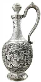 醒酒壺   Wine Decanter 晚清 通高：30.5cm；腹徑：13cm；重：774g 款識(shí)：大吉     這件銀壺造型獨(dú)特，長(zhǎng)頸鼓腹，通身錘揲有人物故事紋，頸部更鏨刻有蕉葉紋、葡萄紋、竹枝紋，并貼焊“巴為芻夫”四字。整件器物僅有上方一球狀壺塞的壺口，并無(wú)設(shè)計(jì)流口，都說(shuō)明這并非盛裝飲品的茶壺，而是一件醒酒壺。西方人不僅愛(ài)喝茶，同樣也愛(ài)美酒，且更多的是飲用葡萄酒，葡萄酒內(nèi)富含的單寧酸常常會(huì)使酒品嘗的口感變澀，這也是葡萄酒需要“醒酒”這一程序的由來(lái)，而中國(guó)銀匠為滿足西方人的飲酒需要，創(chuàng)作出了銀制的醒酒壺。有趣的是，醒酒需要讓酒盡可能大面積的與空氣接觸，使得酒類的單寧酸迅速氧化揮發(fā)，而該壺并無(wú)此特點(diǎn)，這也是由于當(dāng)時(shí)的銀匠缺乏對(duì)葡萄酒的相關(guān)知識(shí)而造成的失誤，只知有“醒酒”這道工序，而不知醒酒的原理，可謂是時(shí)代造就的一個(gè)美麗的誤會(huì)。