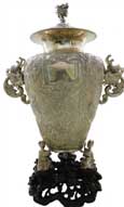 人物故事龍耳瓶   Dragon-shape-handled Vase with Figures and Story Scene Pattern   晚清 帶座通高：57cm；不帶座通高：49cm；腹徑：27cm；不帶座重：3276g 款識(shí)：德昌，HUNGCHONG&CO   銀器實(shí)用性、觀賞性兼具，一直深受西方人的喜愛(ài)，很多時(shí)候都作為禮物和獎(jiǎng)品的不二選擇。這件人物故事龍耳瓶，瓶鈕及兩側(cè)的雙耳皆以龍首為造型設(shè)計(jì)，加之器型高大，整體極具氣勢(shì)。兩側(cè)雙耳是以龍首口中吐出的流水形成下沿，通身布紋為底，通過(guò)錘揲工藝創(chuàng)作出刀馬人物故事圖，底座被設(shè)計(jì)成三名孩童雙手捧持瓶底，下方配一紫檀底座，極具藝術(shù)感。

　　除開整體造型及瓶身上繁復(fù)的紋飾外，最引人著目的當(dāng)屬瓶身中部的方形銘牌，在中日甲午戰(zhàn)爭(zhēng)中，數(shù)位德、英官兵曾在北洋艦隊(duì)上協(xié)助作戰(zhàn)，而在銘牌上的德語(yǔ)銘文，正是向這批德、英軍士們致以最崇高的敬意，也使得這件器物成為了中日甲午戰(zhàn)爭(zhēng)的歷史見(jiàn)證之一，更顯珍貴。