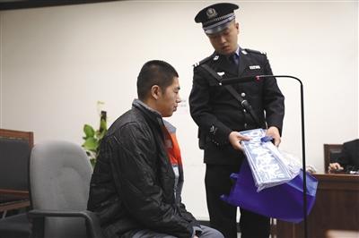 昨日，懷柔法院法庭上，法警向?qū)⒁惠v車賣了8次的被告人劉某出示物證。本版攝影/新京報記者 王飛