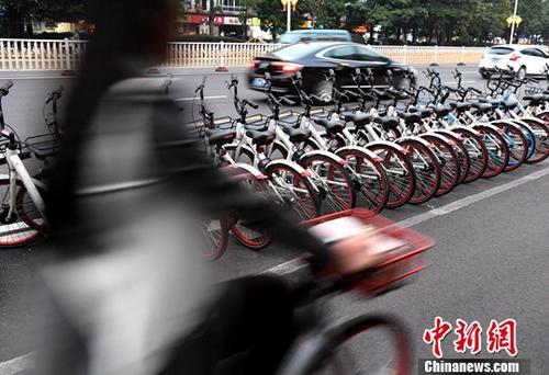 資料圖：路人騎著共享單車(chē)經(jīng)過(guò)“車(chē)堆”。<a target='_blank' href='http://www.chinanews.com/'>中新社</a>記者 張斌 攝
