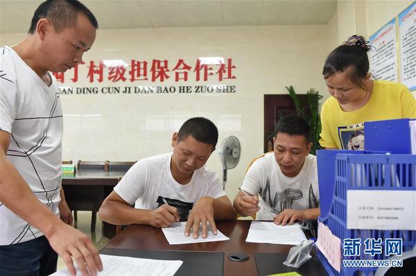 兩名村民在福建武平縣城廂鎮(zhèn)園丁村村級擔(dān)保合作社簽訂反擔(dān)保合同（2017年6月15日攝）。