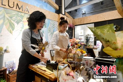 圖為李函儒與媽媽在店里制作花束。 呂明 攝