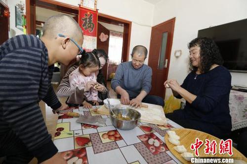 圖為彭秀芳“一家四口”包餃子。(抱著玲玲的是福利院工作人員) 胡貴龍 攝